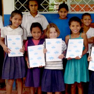 Children holding school supplies made in the Matthew 25 Ministries’ Notebook Manufacturing Center